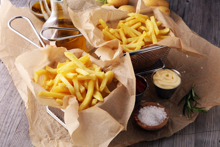 french fries, chips on wooden background with salt