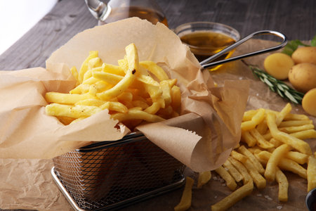 French fries, chips on wooden background with salt