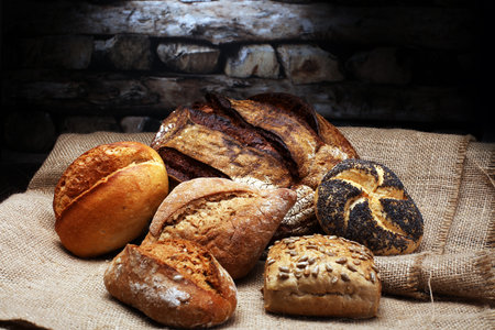 Different kinds of bread and bread rolls on wooden table