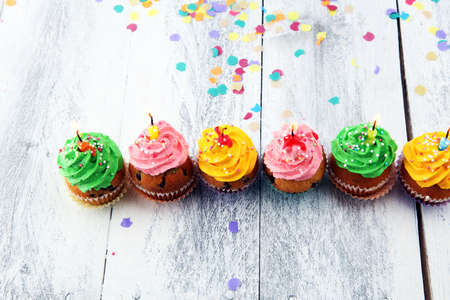 Tasty cupcakes on wooden background. Birthday cupcake in rainbow colorsの写真素材