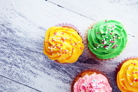 Tasty cupcakes on wooden background. Birthday cupcake in rainbow colorsの写真素材