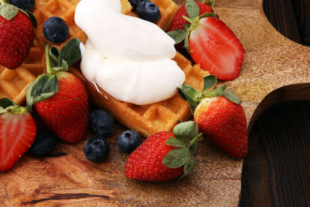 Board of belgian waffles with whipped cream and fresh berriesの写真素材