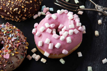 assorted donuts with chocolate frosted, pink glazed and sprinkles donuts.の写真素材