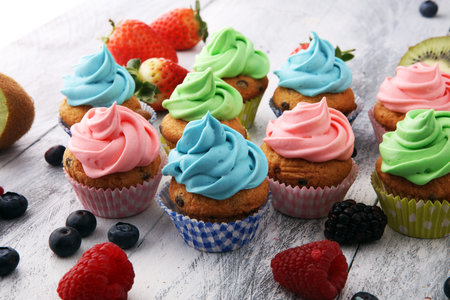 Tasty cupcakes on wooden background. Birthday cupcake in rainbow colorsの写真素材