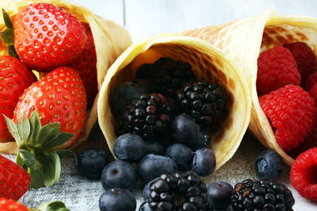 Berries in waffle cones - strawberry, blueberry and raspberry on wooden backgroundの写真素材