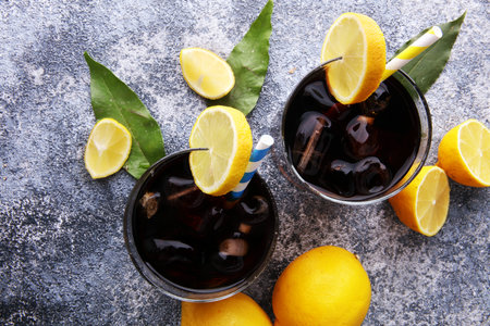 Softdrink with ice cubes, lemon and straw in glass