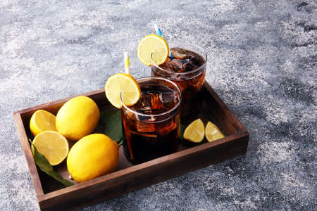 Softdrink with ice cubes, lemon and straw in glassの写真素材