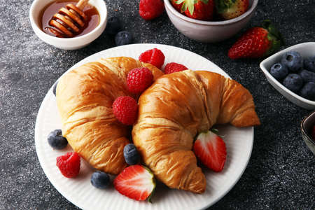 Delicious breakfast with fresh croissants and ripe berries on old marble backgroundの写真素材