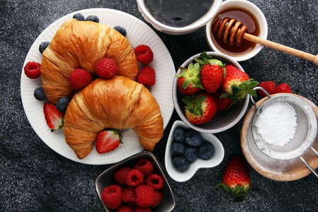 Delicious breakfast with fresh croissants and ripe berries on old marble backgroundの写真素材