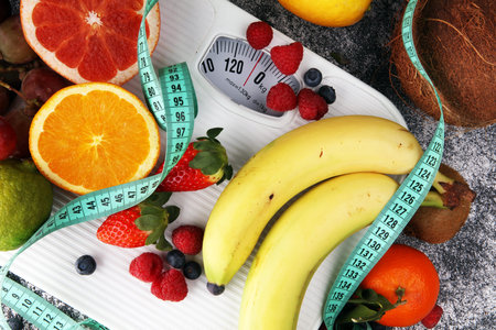 Healthy living or Diet concept. Fruits with measuring tape and a weight scaleの写真素材