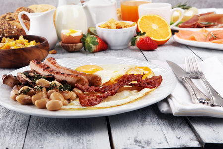 Traditional full English breakfast with fried eggs, sausages, beans, mushroomsand bacon on wooden backgroundの写真素材