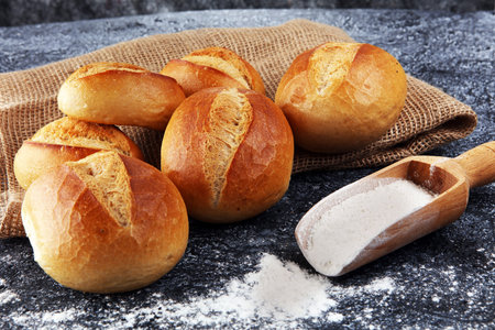 Different kinds of bread and bread rolls on board from above. Kitchen or bakery poster design.