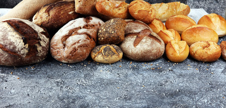 Different kinds of bread and bread rolls on board from above. Kitchen or bakery poster design.の写真素材