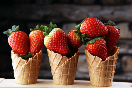 Fresh strawberries in cones on brown wooden background. A group of strawberries.の写真素材