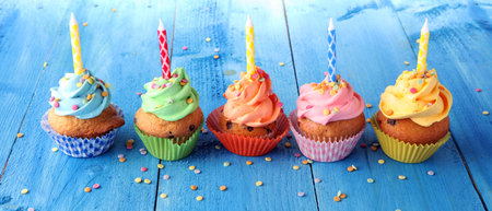 Tasty cupcakes on wooden background. Birthday cupcake in rainbow colorsの写真素材