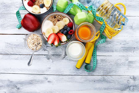 muesli with dairy and fruit, healthy lifestyle. bowl of cereal, fruit and dumbbellの写真素材