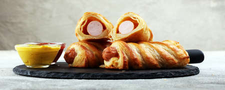 Delicious homemade sausage rolls on a black serving platter.の写真素材