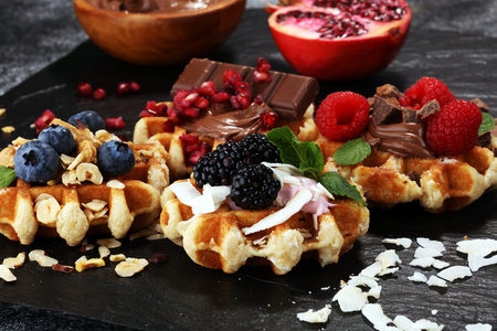 Belgian waffles with pomegranate and raspberries, homemade healthy breakfast with mint and hazelnut butterの写真素材