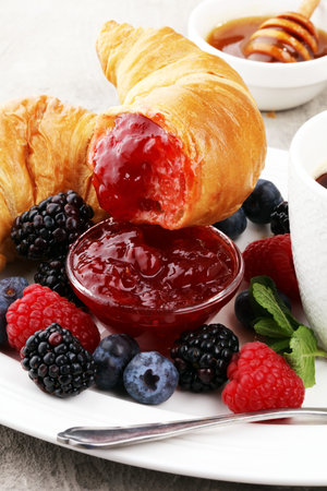 Delicious breakfast with fresh croissants, coffee and ripe berries on old marble backgroundの写真素材