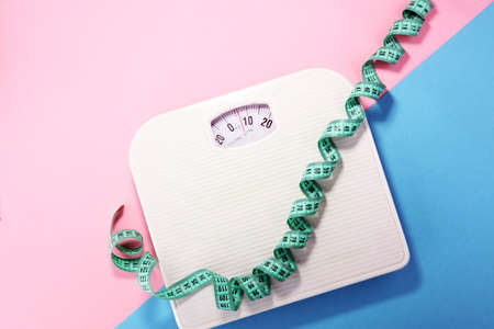 weight and tape measure and concept of diet and healthy lifestyle flat lay on colored paperの写真素材