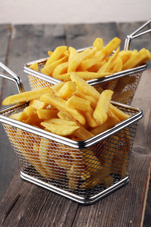 Tasty french fries on wooden table background