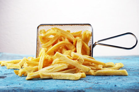Tasty french fries on blue table background