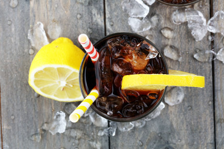 Softdrink with ice cubes, lemon and straw in glassの写真素材