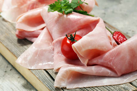 Sliced ham on wooden background. Fresh prosciutto. Pork ham sliced.の写真素材