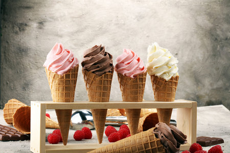Vanilla frozen yogurt or soft ice cream in waffle cone and strawberry, raspberry and chocolate...