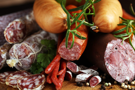 Food tray with delicious salami, ham,  fresh sausages, cucumber and herbs. Meat platter with selectionの写真素材