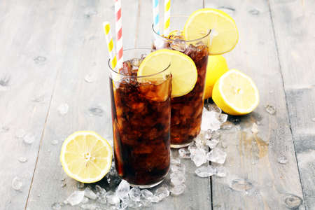 Softdrink with ice cubes, lemon and straw in glassの写真素材