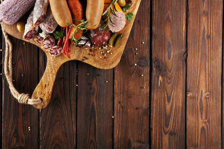 Food tray with delicious salami, ham,  fresh sausages, cucumber and herbs. Meat platter with selectionの写真素材