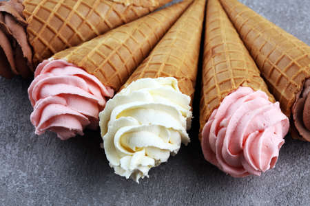 Vanilla frozen yogurt or soft ice cream in waffle cone and strawberry, raspberry and chocolate softice creamの写真素材