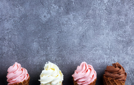 Vanilla frozen yogurt or soft ice cream in waffle cone and strawberry, raspberry and chocolate softice creamの写真素材