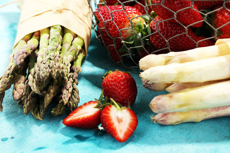 White and green fresh asparagus with a bunch of healthy strawberriesの写真素材