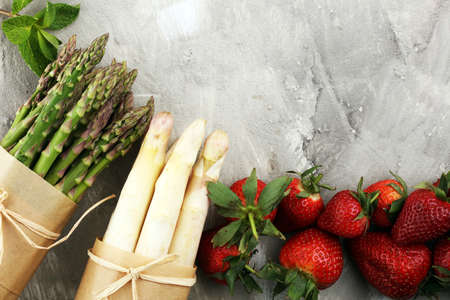 White and green fresh asparagus with a bunch of healthy strawberriesの写真素材