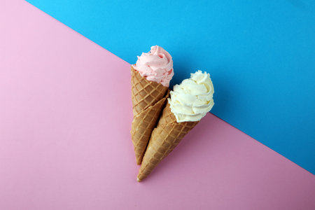 Vanilla frozen yogurt or soft ice cream in waffle cone flat lay on colored paper. 