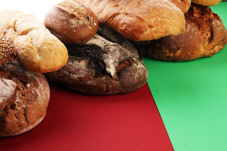 Different kinds of bread and bread rolls flat lay on colored paper. Kitchen or bakery poster design.
