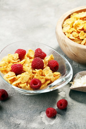 Bowl of Cornflakes and Raspberries for a healthy breakfast concept on rustic grey background