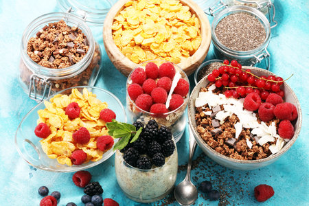 Cereal and ingredients for a healthy breakfast with chia pudding, granola, cornflakes and many...