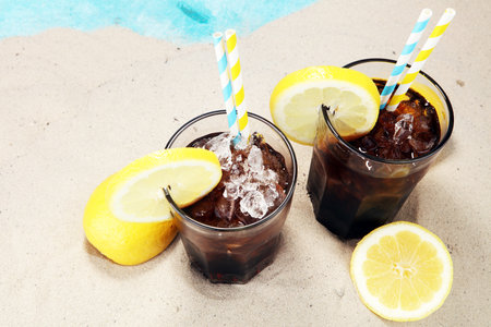 Softdrink with ice cubes, lemon and straw in glass