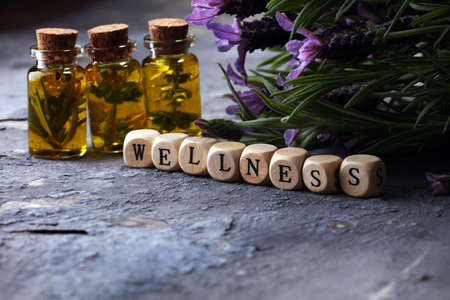lavender oil in a glass bottle on a background of fresh flowers and Wellness sign with wooden cubesの写真素材