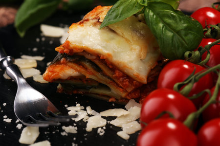 Serving of spicy traditional Italian beef lasagne in a restaurant - bolognese sauce topped with basil leafsの写真素材