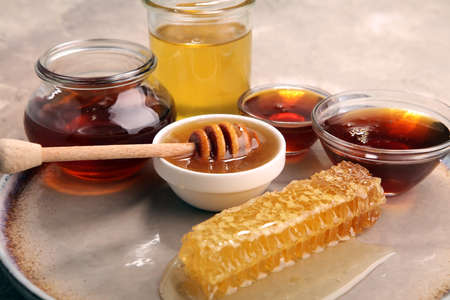Pouring aromatic honey into jar with a honey dipper and a Honeycombの写真素材