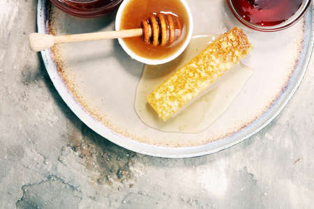 Pouring aromatic honey into jar with a honey dipper and a Honeycombの写真素材