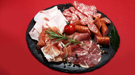 Food tray with delicious salami, ham,  fresh sausages and herbs. Meat platter with selection.