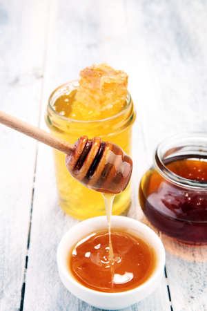 Pouring aromatic honey into jar with a honey dipper and a Honeycombの写真素材