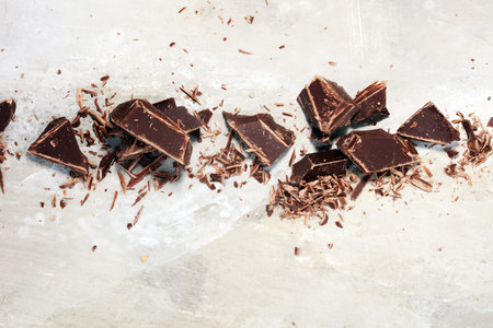 dark chocolate bars on stone table and broken pieces of cocoa.