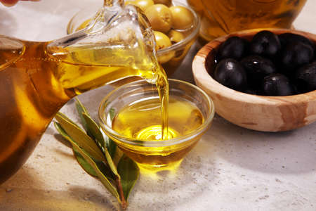 Bottle virgin olive oil and oil in a bowl with some olives.の写真素材
