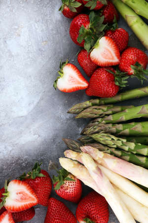 White and green fresh asparagus with a bunch of healthy strawberriesの写真素材